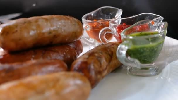 Würstchen vom Grill liegen auf einem Teller neben mehreren Soßen. Fleischgerichte vom Grill. — Stockvideo