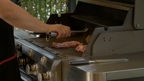 Cocinero profesional utiliza pinzas de metal para entregar los filetes de carne que se cocinan en una parrilla de gas. Cocinar comida al aire libre. Deliciosa comida saludable . — Vídeos de Stock