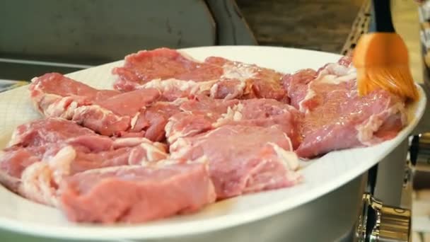 Σεφ επιχρίσματα κομμένη κομμάτια από το ωμό κρέας με το ελαιόλαδο για το μαγείρεμα μπριζόλες στα κάρβουνα. Η συνταγή για το μαγείρεμα στη σχάρα. — Αρχείο Βίντεο