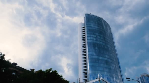 Video de TimeLapse. Una vista desde abajo en un gran centro de negocios de vidrio sobre un fondo de nubes grises en movimiento. — Vídeo de stock