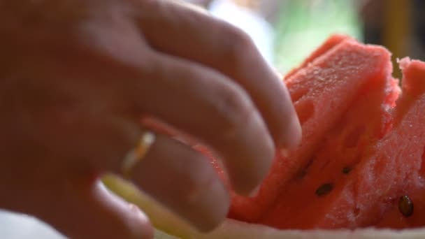 Menselijke hand neemt en pakt een stuk van rijpe rode watermeloen die professioneel wordt gesneden. Vitaminen in de natuur. Gezonde levensstijl. Het belangrijkste eten is fruit. — Stockvideo