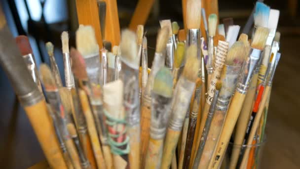 Beaucoup de pinceaux différents se tiennent debout dans des vases. Équipement professionnel de l'artiste. Studio d'art. Focus de la caméra se déplace par des objets . — Video