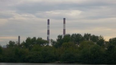 Büyük Endüstriyel boru su üzerinde gemiden görüntüleyin. Gün batımında Fabrika bacaları. Çevre kirliliği.