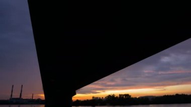 Fener ile büyük yüksek köprünün altından sunset Bulvarında Nehri üzerinde görüntüleyin. Şehrin iki banka bağlantı bina mimari. Büyük yapı. Gemi su üzerinde yürümek.