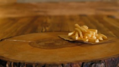 Eldiven bir sulu siyah burger büyük Beşamel sos ve sebze patates kızartması yanında ahşap tahta üzerinde ellerine. Sağlıksız fast food.