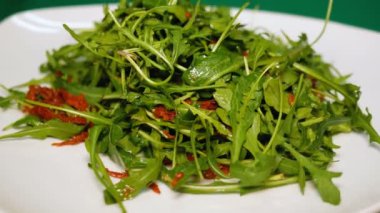 Roka ve kurutulmuş domates salatası beyaz tabak içinde döndürün. Sağlıklı bir diyet yemek kapatın. Olağandışı tarifi yemekleri.