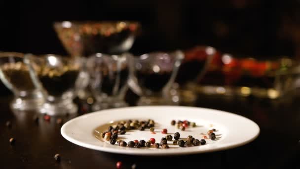 Varieties of peppercorns on a white plate and in transparent containers. The focus of the camera moves from the foreground to the rear. — Stock Video