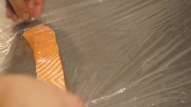 İnsan elleri dilimlenmiş somon fileto bir parça almak ve pey şal sarın. Donma için balık hazırlama.