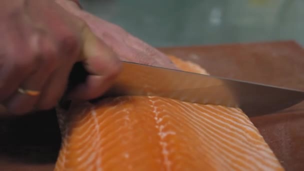 Manos de chef macho cortan grandes filetes de salmón con un cuchillo de cocina profesional de cerca . — Vídeos de Stock