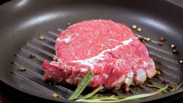 O bife de carne é frito com uma folha de alecrim e pimenta em uma panela lentamente rotativa . — Vídeo de Stock