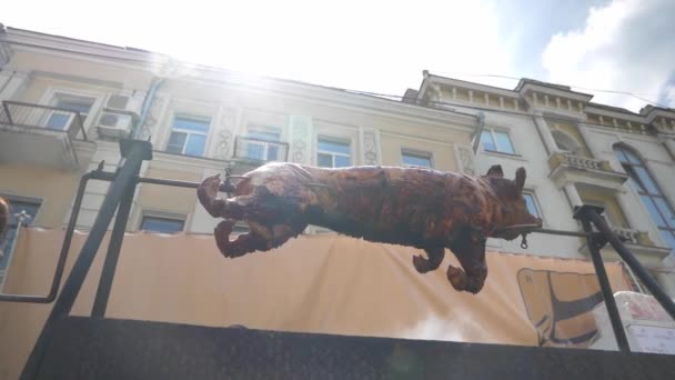 Un cerdo entero en un pincho está asando a la parrilla al aire libre en una gran parrilla . — Vídeos de Stock