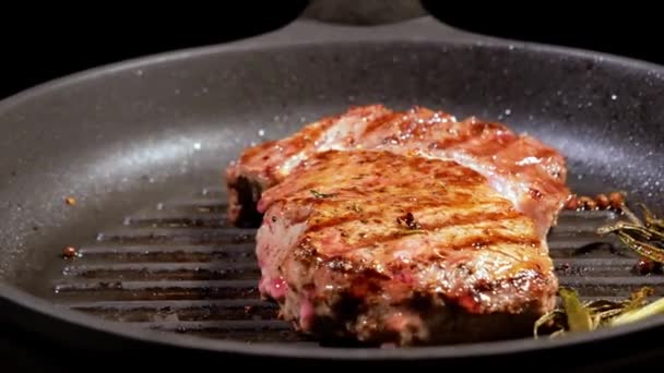Вишневі помідори кладуть на обертову сковороду, на якій смажать м'ясний стейк . — стокове відео