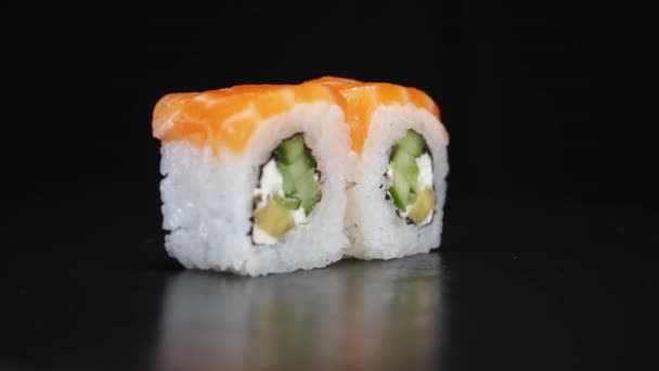 Los rollos de sushi giran sobre fondo negro. Dispara de cerca. Filadelfia queso y salmón en la comida japonesa. — Vídeos de Stock