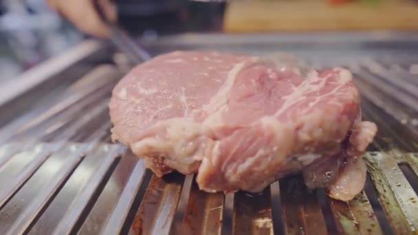 Pezzo di carne cruda è turno con pinze sulla griglia. Cucinare cibo malsano. — Video Stock