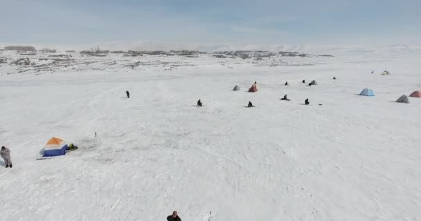 氷の凍結する冬の山の湖で漁師 — ストック動画