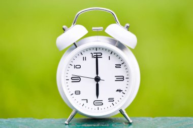 Yeşil zemin üzerine beyaz çalar saat.