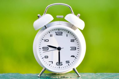 Yeşil zemin üzerine beyaz çalar saat.