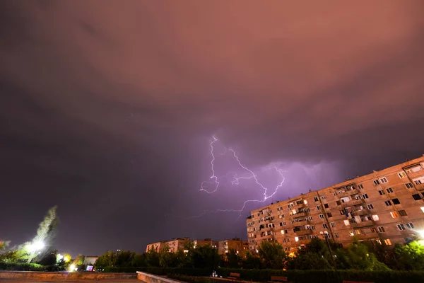 Lightning in the night sky over houses.