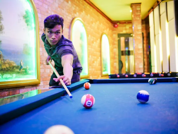 Junger Mann spielt Billard im bunten Club - mit weißer Kugel zum Schießen — Stockfoto