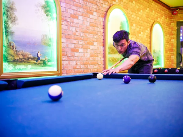 Junger Mann spielt Billard im bunten Club - mit weißer Kugel zum Schießen — Stockfoto