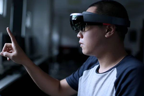 Young asian student trying Mixed reality with VR glasses in the laboratory. Gesture of men when using Virtual Reality headset