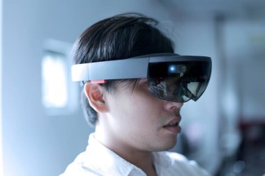 Asyalı iş adamı karışık gerçekliği denemek için Hololens gözlüğü takıyor.