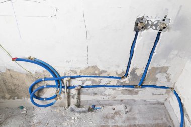 Duvardaki, Polipropilen Pex evde sıhhi tesisat su boruları yapılmıştır. Kanalizasyon boruları bir daire iç banyoda yükleme yenileme çalışmaları sırasında. Mavi plastik drenaj borusu için kullanılan su