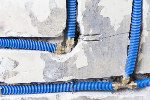 Water pipes made of polypropylene PEX in the wall, plumbing in the house. Installation of sewer pipes in a bathroom of an apartment interior during renovation works. Blue plastic drain pipe for used water