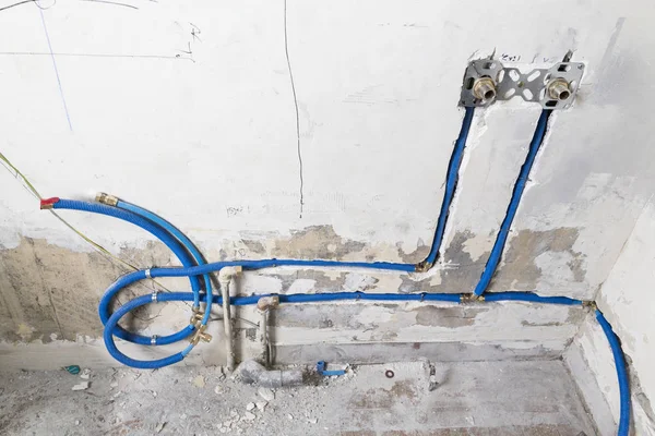 Duvardaki, Polipropilen Pex evde sıhhi tesisat su boruları yapılmıştır. Kanalizasyon boruları bir daire iç banyoda yükleme yenileme çalışmaları sırasında. Mavi plastik drenaj borusu için kullanılan su