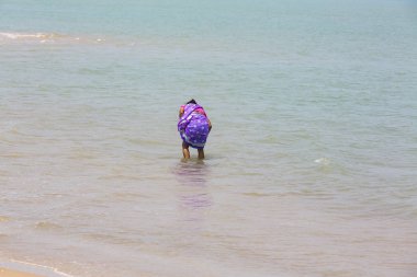 Kimliği belirsiz bir genç kadın kız güzel güneşli sabah Danushkodi plajda yürüyor