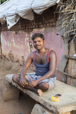 PONDICHERY, PUDUCHERRY, TAMIL NADU, INDIA - SEPTEMBER CIRCA, 2017. An unidentified elderly man poses for a photo, as he sits next to his house, inside Pondichery city clipart