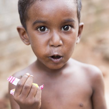 Pondichery, Puducherry, Tamil Nadu, Hindistan - Eylül yaklaşık, 2017. Kimliği belirsiz bir yoksul Hintli çocuk sokakta onun aperatif yemek portresi. Vlose-up