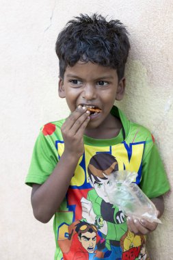 Pondichery, Puducherry, Tamil Nadu, Hindistan - Eylül yaklaşık, 2017. Kimliği belirsiz bir yoksul Hintli çocuk sokakta onun aperatif yemek portresi. Vlose-up