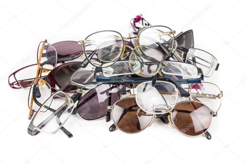 Old used eye reading glasses speclacles stacked in a pile on a white background.