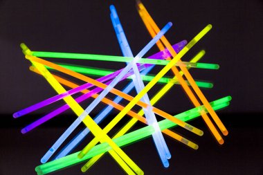 Renkli floresan ışık neon kızdırma ayna yansıması siyah arka plan üzerinde sopa. Sarı mavi pembe turuncu yeşil mor kızdırma sopa