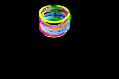 Renkli floresan ışık neon glow stick Bileklik kayış Bileklik ayna yansıması siyah arka plan üzerinde. Sarı mavi pembe turuncu yeşil mor kızdırma sopa