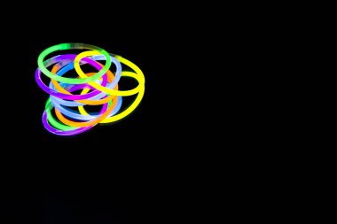 Renkli floresan ışık neon glow stick Bileklik kayış Bileklik ayna yansıması siyah arka plan üzerinde. Sarı mavi pembe turuncu yeşil mor kızdırma sopa