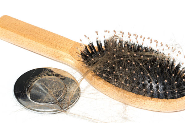 Hair loss on washbasin. Long brown hair with wood brush on white basin in the bathroom. Healthcare concept