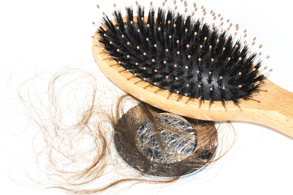 Hair loss on washbasin. Long wet brown hair with wood brush on white basin in the bathroom. Healthcare concept