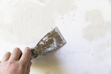Bir kadın elinin alçı dolgu duvara eski metal spatula ile yakın çekim