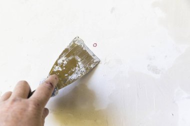 Bir kadın elinin alçı dolgu duvara eski metal spatula ile yakın çekim