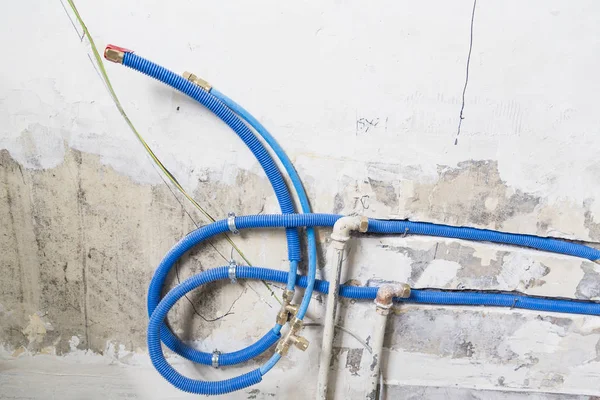 水パイプは壁のポリプロピレンの Pex の家の配管から成っています 改装工事中にアパート インテリアのバスルームの下水管の設置使用水の青いプラスチック製の排水管 — ストック写真