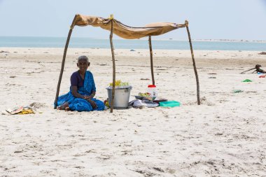 Yaklaşık, Danushkodi, Pamban Adası, Tamil Nadu, Hindistan - 2018 Mart. Kimliği belirsiz bir kadın Danushkodi beach bir çadırın altında bir müşteri için meyve fıstık satmak.