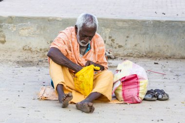 Yaklaşık, Rameswaram, Rameshwaram, Pamban Adası, Tamil Nadu, Hindistan - 2018 Mart. Kimliği belirsiz Sadhus hacılar adam portresi yolda yemek için bekleyen oturan Turuncu elbise giymiş. Bir Hindu hac inanç ve kitle sacre banyoda olduğunu