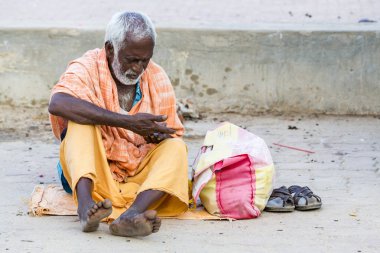 Yaklaşık, Rameswaram, Rameshwaram, Pamban Adası, Tamil Nadu, Hindistan - 2018 Mart. Kimliği belirsiz Sadhus hacılar adam portresi yolda yemek için bekleyen oturan Turuncu elbise giymiş. Bir Hindu hac inanç ve kitle sacre banyoda olduğunu