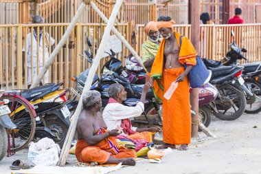 Yaklaşık, rameshwaram, Pamban Adası, Tamil Nadu, Hindistan - 2018 Mart. Bir grup kimliği belirsiz Sadhus hacı Gıda için bekleyen road, sokakta oturan Turuncu elbise giymiş. Bu inanç bir kitle Hindu Hac ve Kutsal içinde banyo