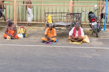 Yaklaşık, rameshwaram, Pamban Adası, Tamil Nadu, Hindistan - 2018 Mart. Bir grup kimliği belirsiz Sadhus hacı Gıda için bekleyen road, sokakta oturan Turuncu elbise giymiş. Bu inanç bir kitle Hindu Hac ve Kutsal içinde banyo