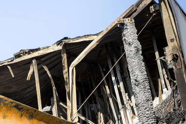 Damaged roof industry supermarket after arson fire with burn debris of twisted metal structure after intense burning fire disaster ruins waiting for investigation for insurance