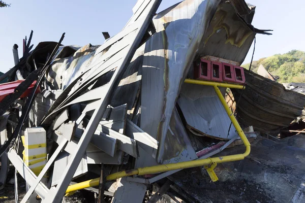 damaged industry supermarket metallic facade after arson fire with burnt debris after intense burning fire disaster ruins waiting for investigation for insurance, with gas emergency stop system protection