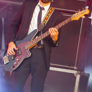 Bir adam gitarist bas gitar alet sahne rock müzik performans. Sahne açık ışık. Otantik ile zorlu ışık koşullarında yüksek ISO çekim.